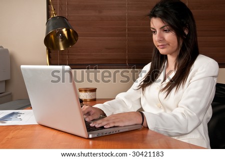 Young woman working at computer in office desk, in small business.