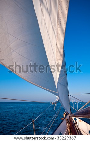 Sailboat navigates in the ocean at sunset time. Space for copy.