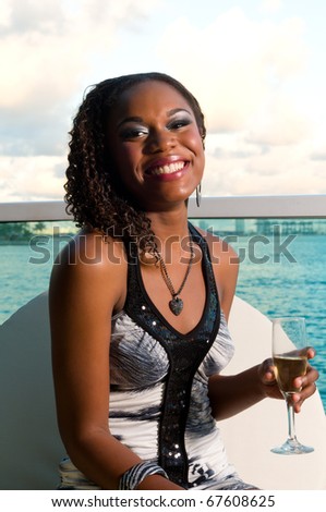 Young african american enjoys a glass of champagne in a terrace with ocean view.
