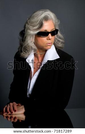 Executive woman in her 50s wearing sunglasses and looking serious.