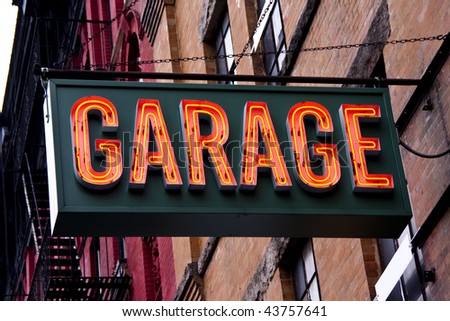 A lit garage neon sign in an urban setting.