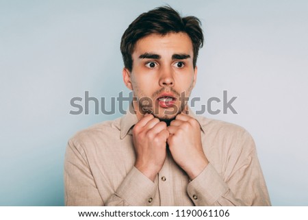 scared shocked terrified frightened startled man clutching hands to his face. portrait of a young brunet guy on light background. emotion facial expression. feelings and people reaction concept. Сток-фото © 