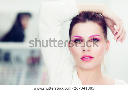 The woman with a bright pink make-up and pink eyebrows. Studio portrait.