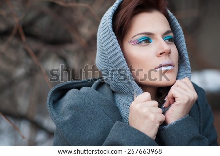 The woman with a creative make-up wraps up in a gray coat