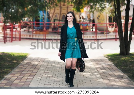 the happy young woman with long hair in a coat walks down the street
