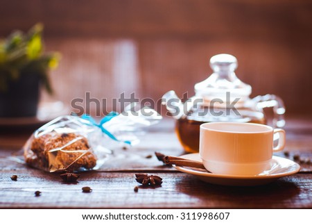 teapot, cup of green tea, cinnamon, cardamom and the vegetarian cookies which are beautifully packed into gift packing. Dark wooden background
