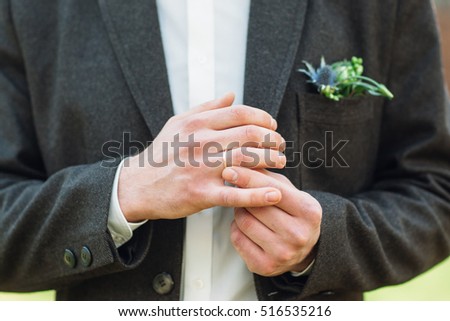 Groom fit on his wedding ring on right hand. Close-up of man in suit hands fidgeting golden wedding ring