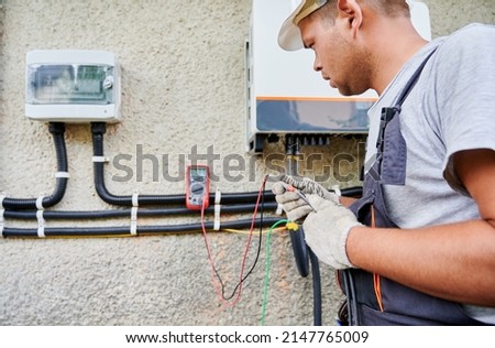 Man electrician installing solar panel system. Inspector in gloves making electrical wiring inverter and electric box. Concept of alternative and renewable energy. Photo stock © 