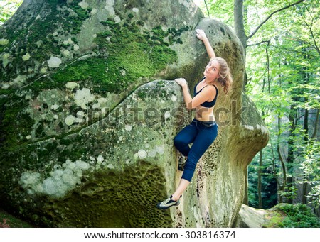 Young woman climbing on large boulders outdoor summer day