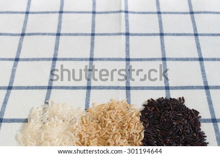 Food background with three groups of rice varieties on bottom of image over table cloth background