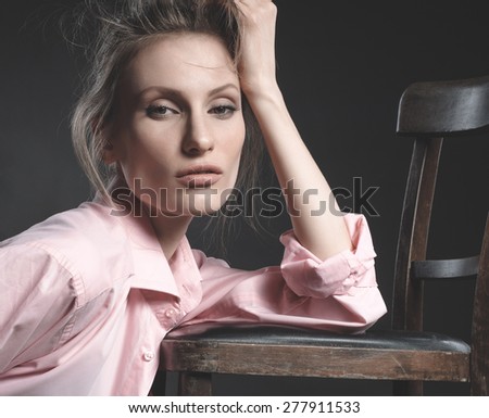 High fashion look, closeup beauty portrait of beautiful young woman model with natural makeup with perfect clean skin sitting on chair. Beautiful girl with elegant hairstyle. Fashion photo