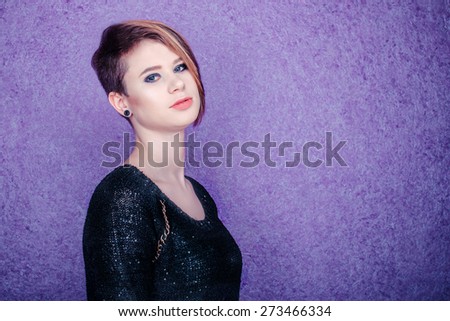 Beautiful girl in black shirt on a purple background with short haircut sideways