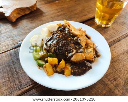 A plate of Tahu Tek, is one of the typical dishes of East Java.  Consisting of  fried tofu and rice cake, omelette, bean sprouts and sliced ​​cucumber, the doused with thick black petis seasoning Stok fotoğraf © 