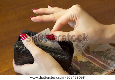 Female hands take money out of the purse.