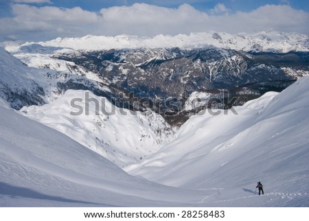 Small human walking on the snow covered mountains