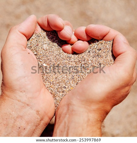 Hands in shape of hearts filled with sand