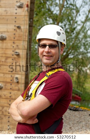 Adult men with helmet is posing before climbing wall