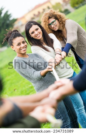 Multiracial People Playing Tug of War. Three Women playing against Three Men and Looking at them
