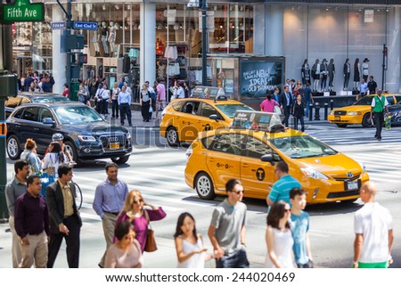 NEW YORK, USA - AUGUST 28, 2014: Crowded 5th Avenue with tourists on sidewalk and yellow cabs on the street.