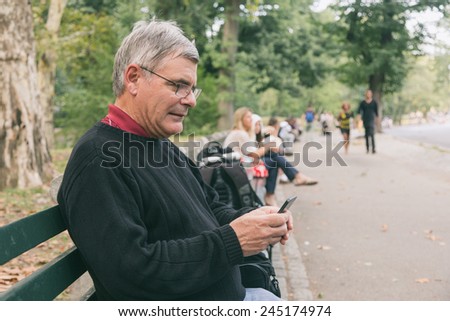 Retired Senior Man at Park, Typing on Mobile, Smiling Expression