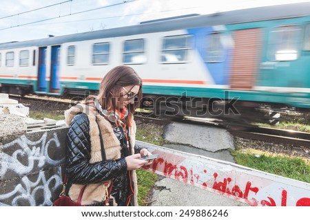 Beautiful Young Woman Walking in Balance on Railway Tracks. The Railroad is in a Residential Aerea. The Girl has a Casual Look.