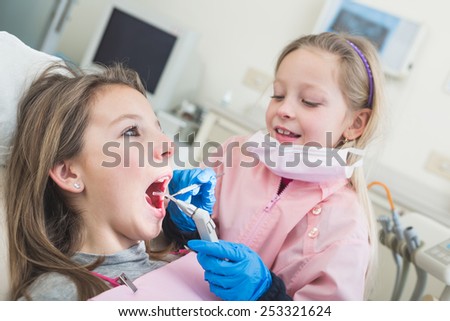 Little Girls Dentist and Patient During Dental Examination. Girl Pretending to be a Dentist is Examining Teeth of another Girl. Funny and Playful representation of Dentist and Dental Theme.