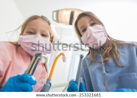 Little Female Dentists Holding Dental Tools Looking at Camera. Personal or Patient Point of View, POV. Girls are holding Drill, Mirror, Aspirator and Spreader. Funny Image.