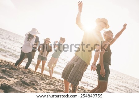 Multiracial group of friends having a party at beach. There are asiatic, black and caucasian persons. Friendship, immigration, integration concepts. Also refers to summer and party.