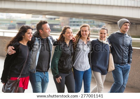 Group of friends walking and having fun together in London. They are four girls and two boys in their twenties, friendship and lifestyle concepts, autumn clothing