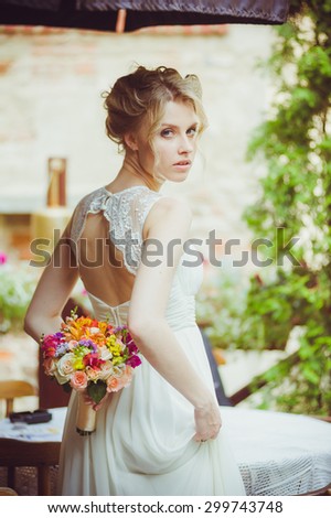 Smiling beautiful bride on wedding day with a big bouquet near church.