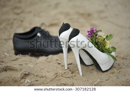 Bride shoes and groom shoes on the sand with wedding bouquet
