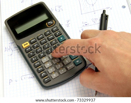 Scientific calculator on notebook paper and a hand
