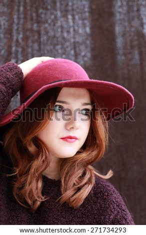 Portrait of a pretty teenage girl with red hair and floppy hat