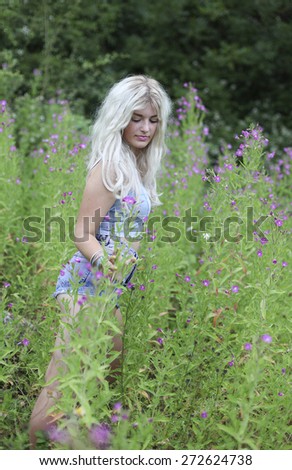 Beautiful young woman with long blonde hair in long grass