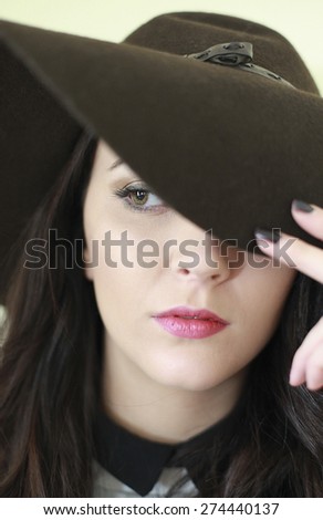 Portrait of a beautiful woman wearing a hat which is covering one eye.