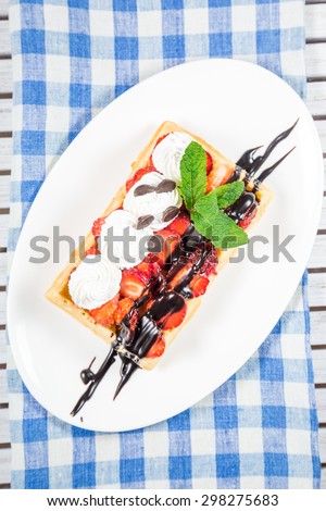 Plate of belgian waffles with ice cream, caramel sauce and fresh fruit