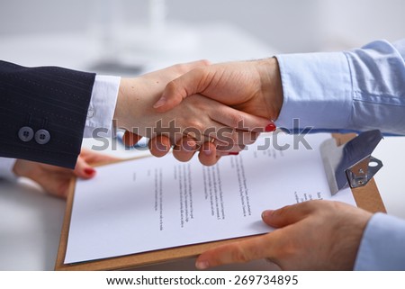 Image of business partners handshaking over business objects