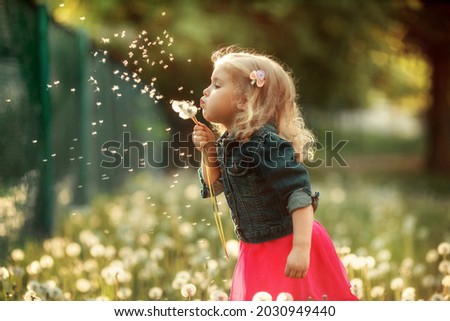 Portrait of happy girl. Child is smiling in spring day. Kid is enjoying spring. Sunny day. Blonde girl is blowing dandelion. Outdoor, close up. Сток-фото © 