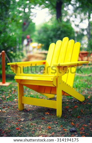 yellow wooden chair on the grass. Fallen leaves. Shallow depth of field