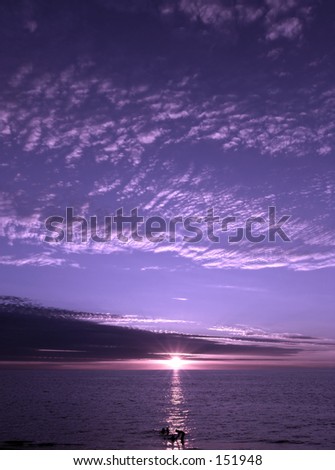 Purple sunset shining on people in the water