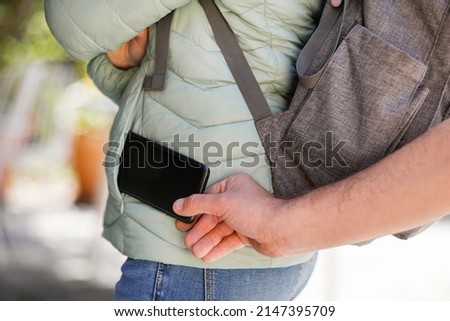 Detail of a man's hand stealing a mobile phone from a girl's pocket Foto stock © 