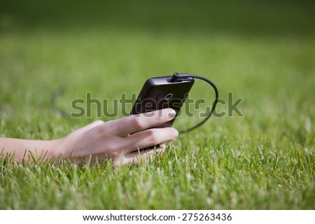 Girl with smart-phone outdoors in park. Closeup of female hands and smart phone