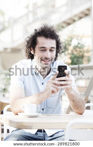 Handsome man watching social media in a smart phone in a restaurant terrace