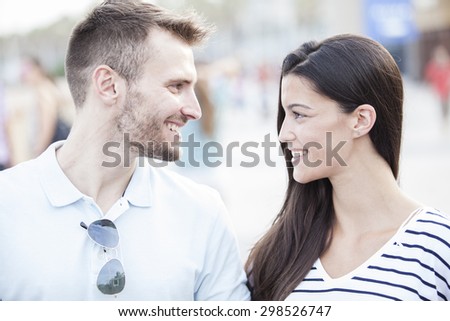 Funny couple laughing with a white perfect smile and looking each other outdoors with unfocused background