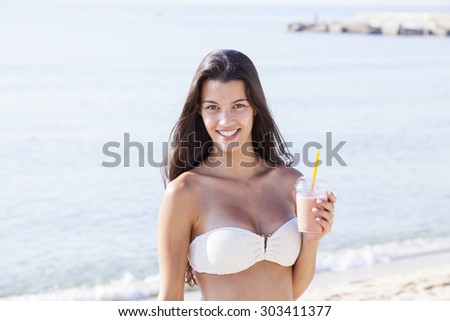 beautiful fun and joy brunette smiling woman in white bikini drink smoothie in front of the beach