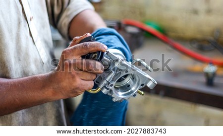 A local mechanic is cleaning the throttle body of a car with cloth and spray and is cleaning all the dust from the system for better air and fuel intake and fuel flow ストックフォト © 