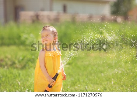 Funny babe watering the water from a hose in the garden