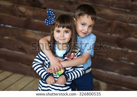 Portrait of a cute little brother hugging his little sister. A wooden background