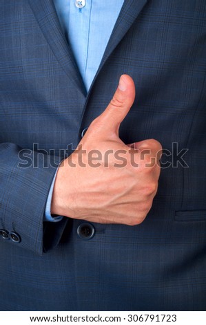 A man in a suit hand gesturing thumbs up