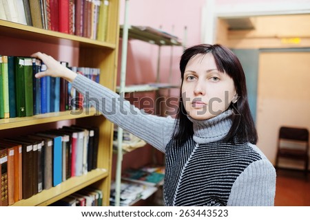 Woman in the library takes the book from the shelf